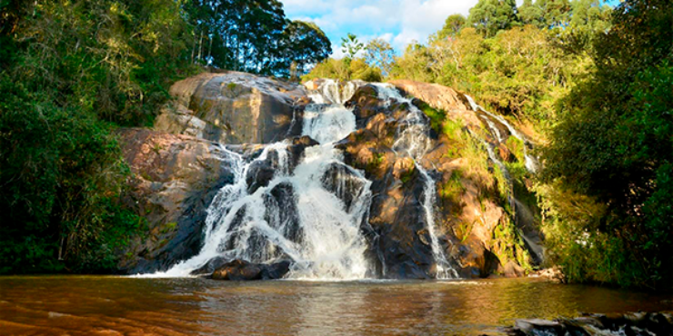 Cachoeira repleta de rochas banha o lago em dia ensolarado no município de Bueno Brandão, no interior de Minas Gerais. 